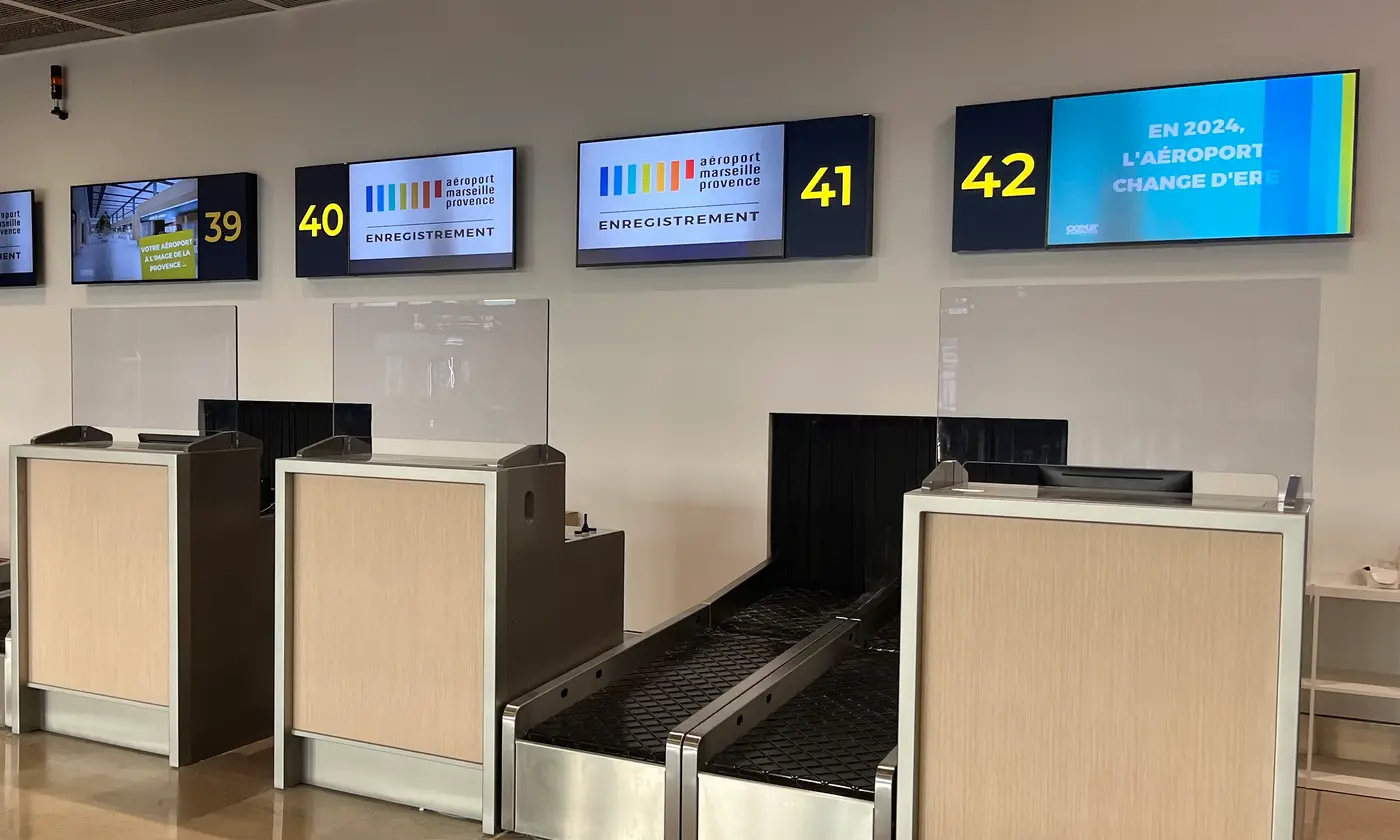Les banques d'enregistrement 39 à 42 du terminal 1 rénové de l'aéroport Marseille-Provence, écrans allumés au-dessus des comptoirs.