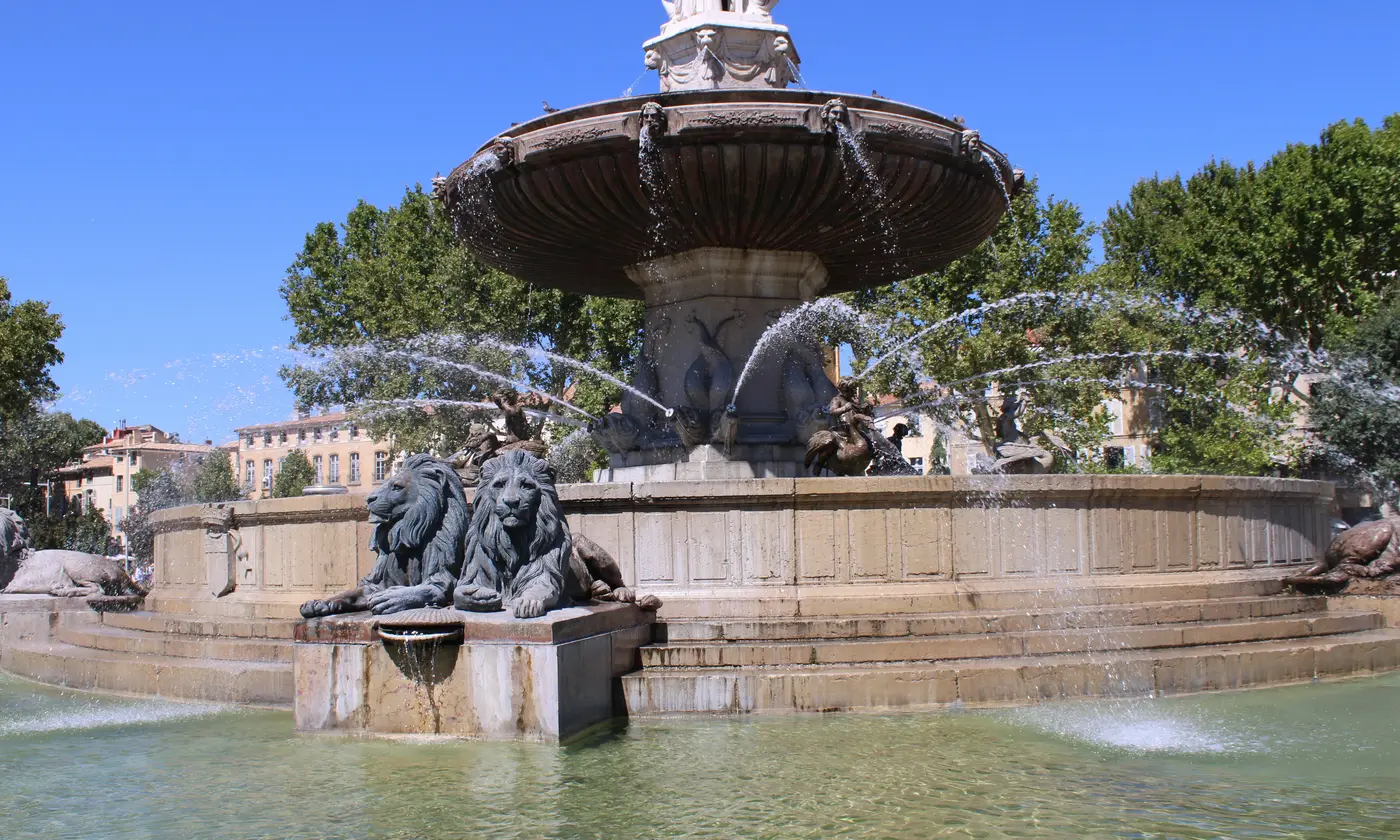 La fontaine de la Rotonde à Aix-en-Provence, ses lions de bronze et ses jets d'eau sous un ciel bleu