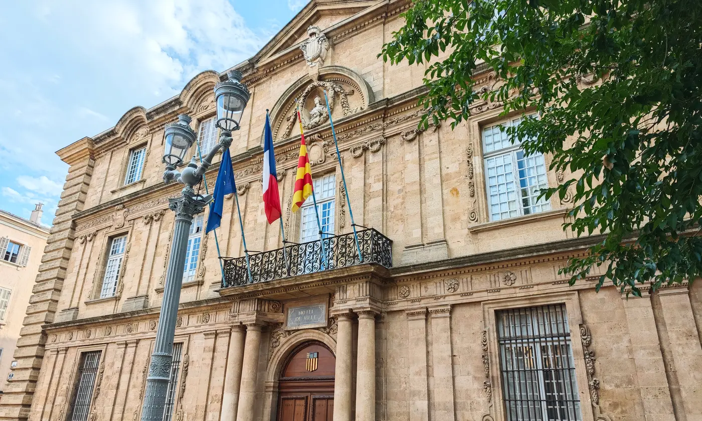 La façade de l'hôtel de ville d'Aix-en-Provence avec ses drapeaux et son balcon en fer forgé