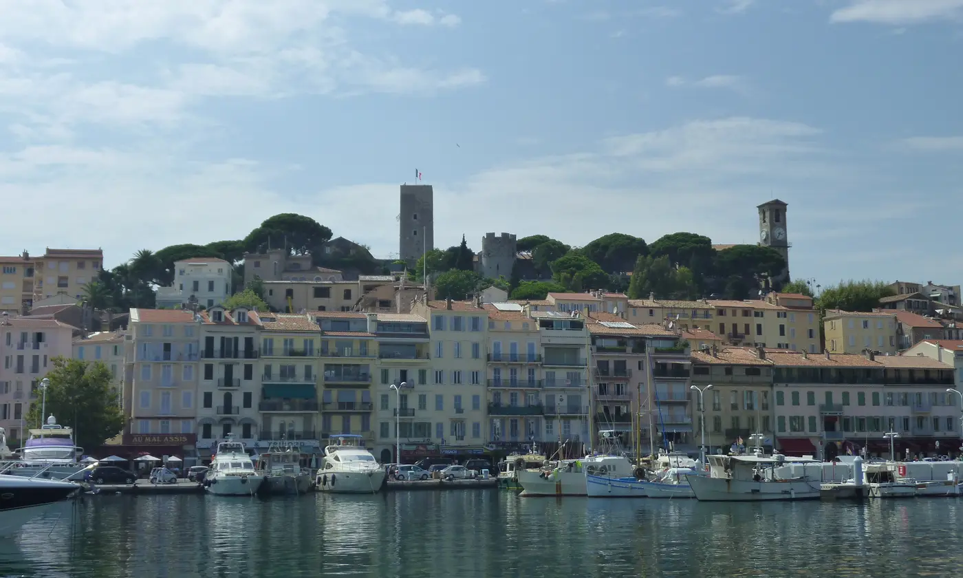 Bateaux amarrés au Vieux Port devant les façades pastel, avec la tour du Suquet et le clocher en toile de fond, Cannes