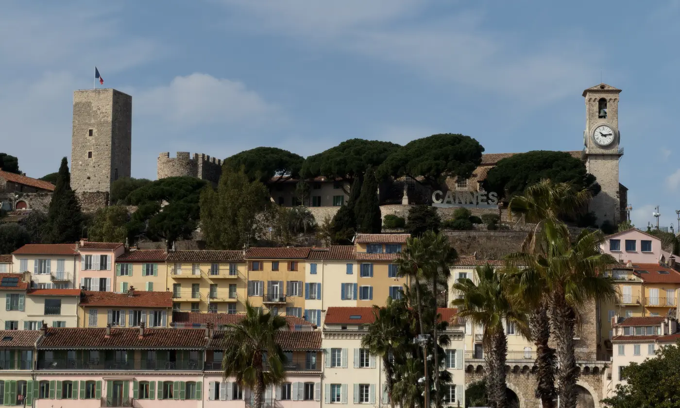 La colline du Suquet avec sa tour médiévale, son clocher à horloge et les lettres CANNES au-dessus des façades colorées de la vieille ville