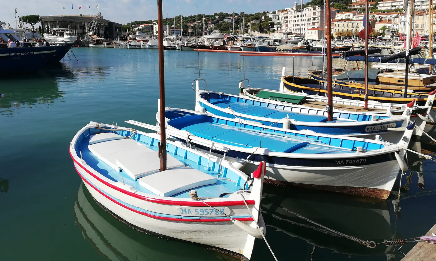 Barques de pêche traditionnelles aux couleurs vives amarrées devant les façades du village, port de Cassis
