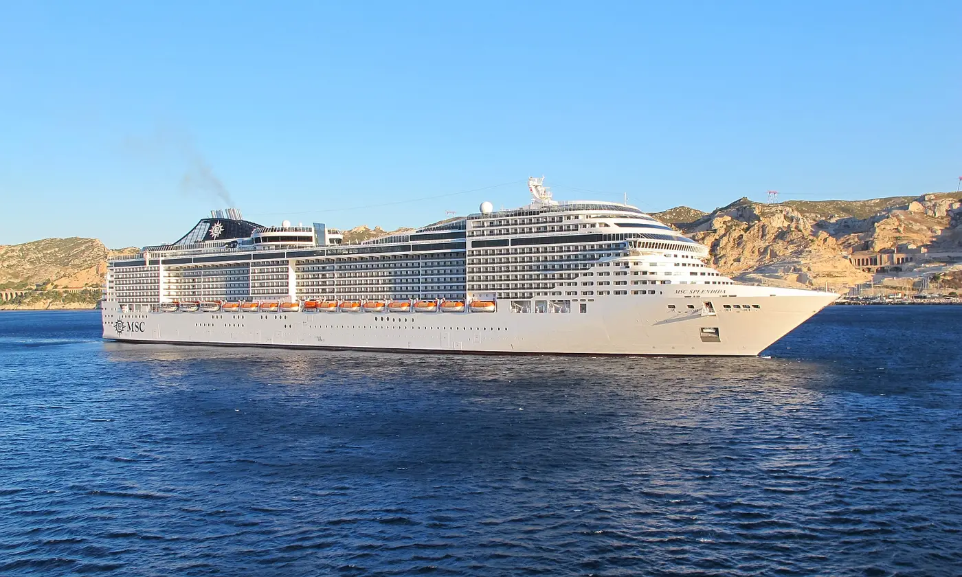 Le paquebot MSC Splendida naviguant en mer devant la côte calcaire de Marseille, dans la lumière dorée du matin