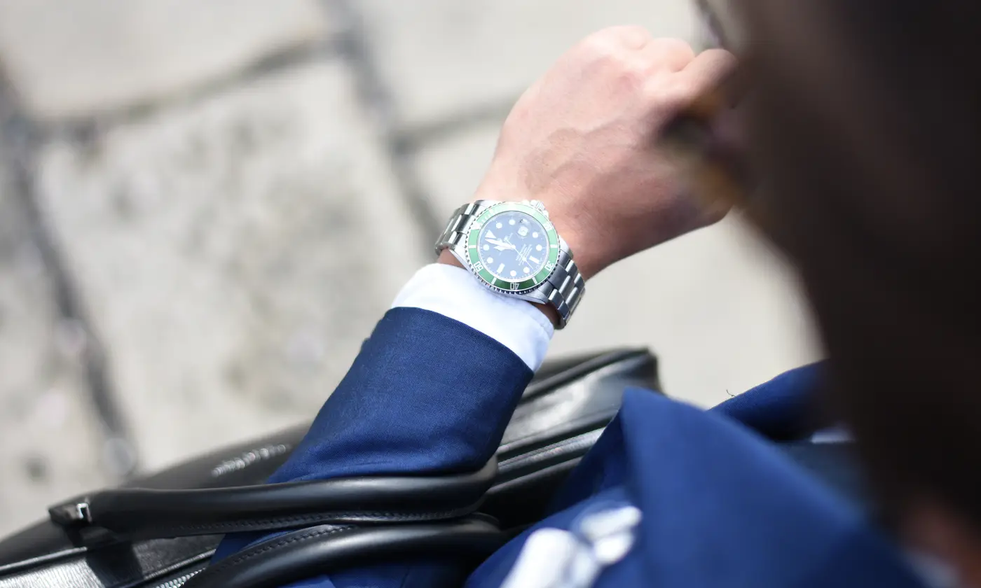 Homme d'affaires en costume bleu consultant sa montre, mallette en cuir noir à l'épaule