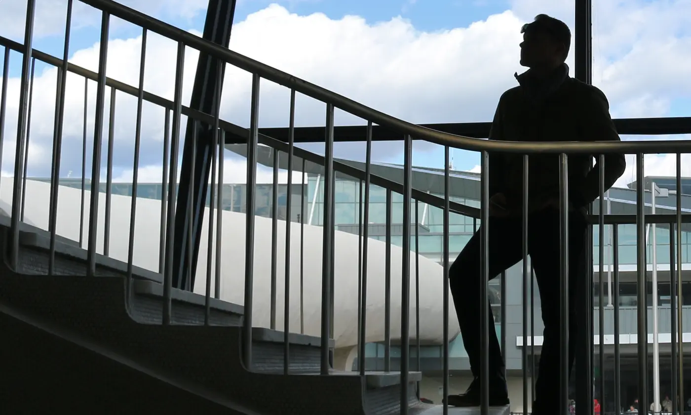 Silhouette d'un voyageur devant les baies vitrées d'un terminal d'aéroport, terminal en arrière-plan