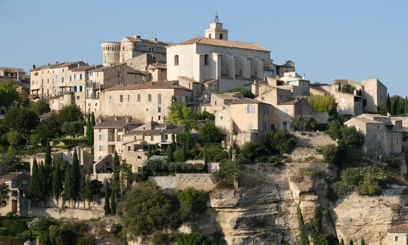 Le village perché de Gordes en pierre dorée, château et clocher au sommet de la falaise, lumière du soir