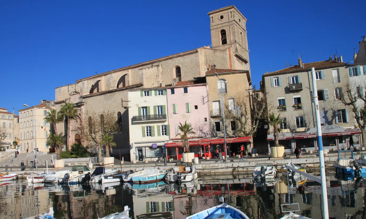 Le Vieux Port de La Ciotat sous un ciel bleu profond, barques et reflets devant l'église Notre-Dame-de-l'Assomption, La Ciotat