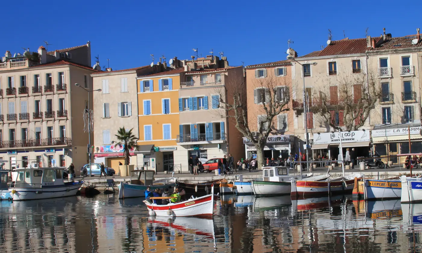 Barques traditionnelles amarrées et façades colorées se reflétant dans l'eau du Vieux Port, La Ciotat