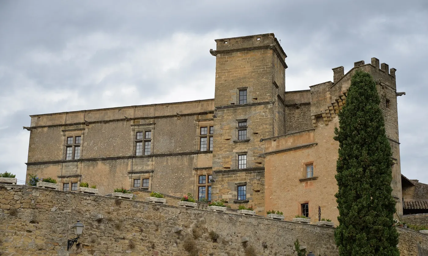 Le château Renaissance de Lourmarin au-dessus de ses remparts, un cyprès devant la tour
