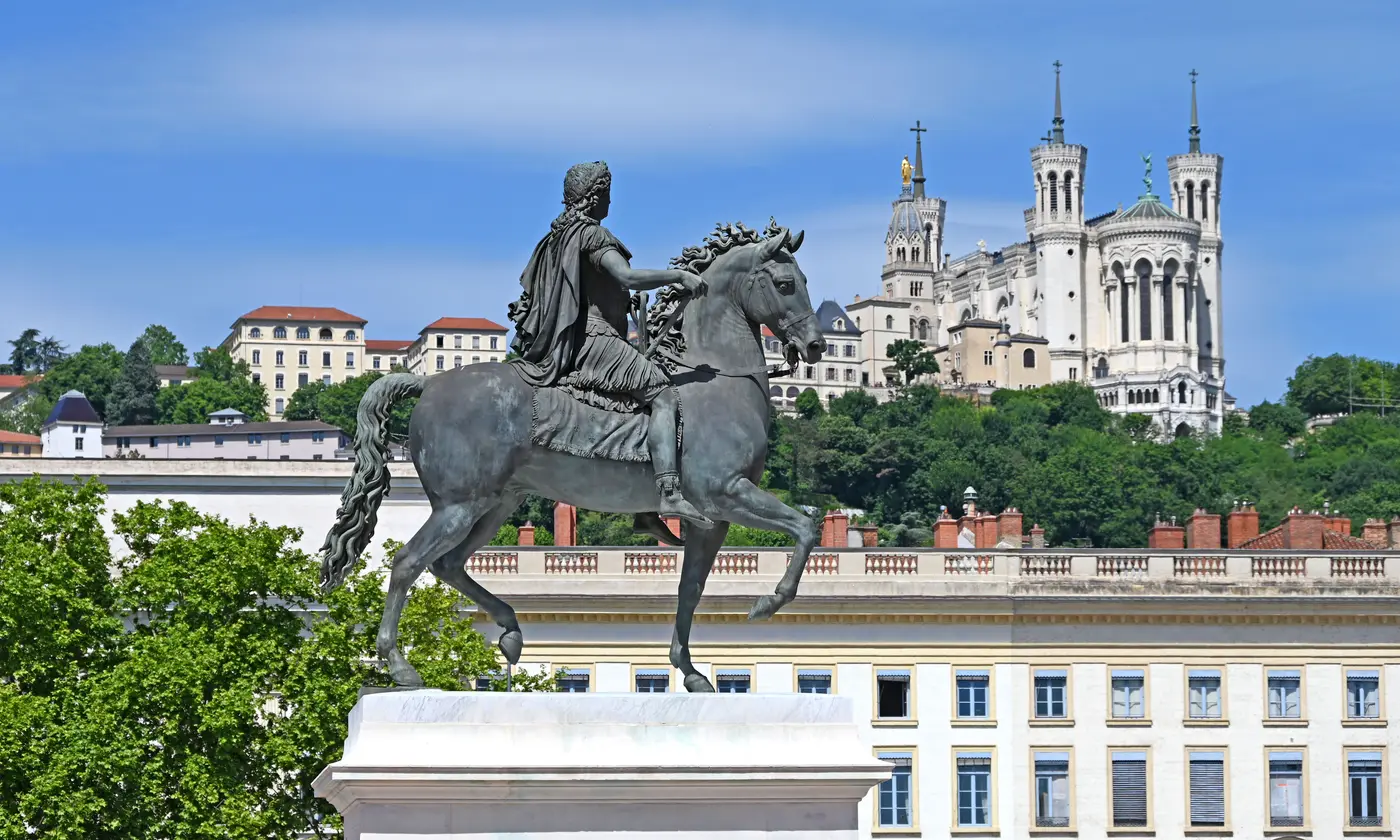 Statue équestre de Louis XIV sur la place Bellecour, avec la basilique Notre-Dame de Fourvière en arrière-plan, Lyon