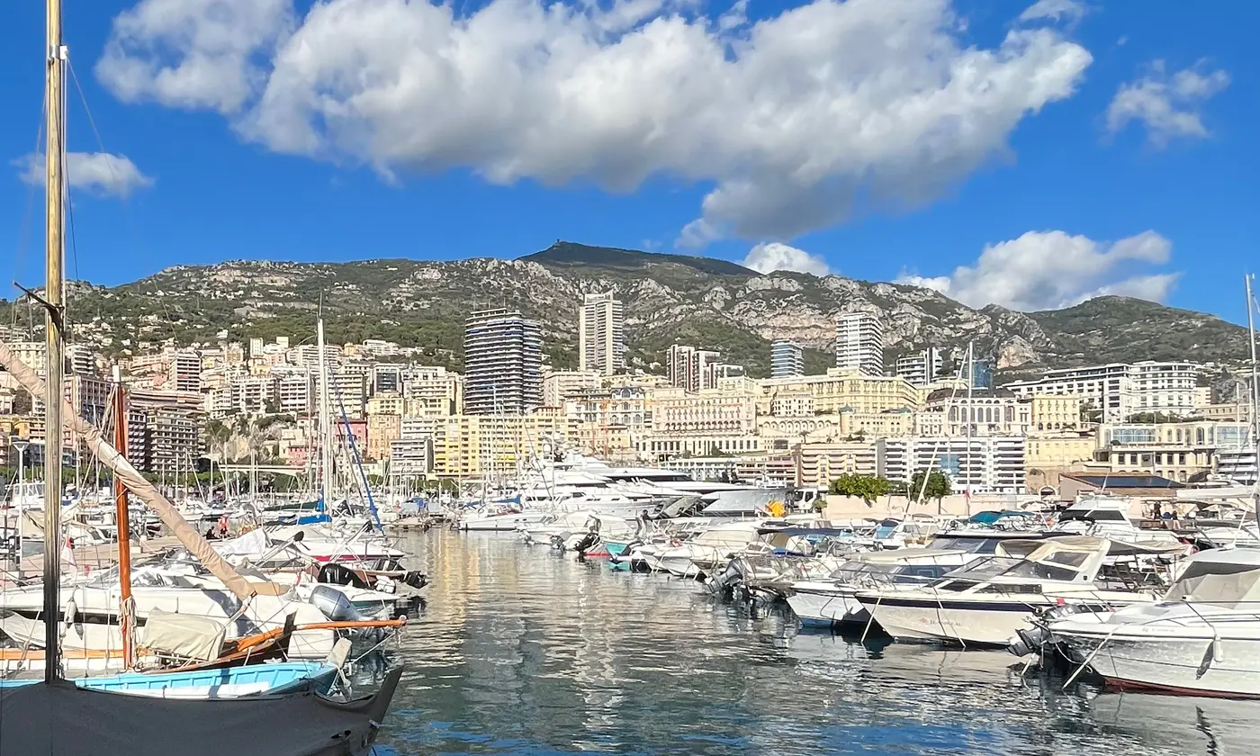 Pointu traditionnel et bateaux amarrés au Port Hercule devant les immeubles de Monte-Carlo et le mont Agel, Monaco