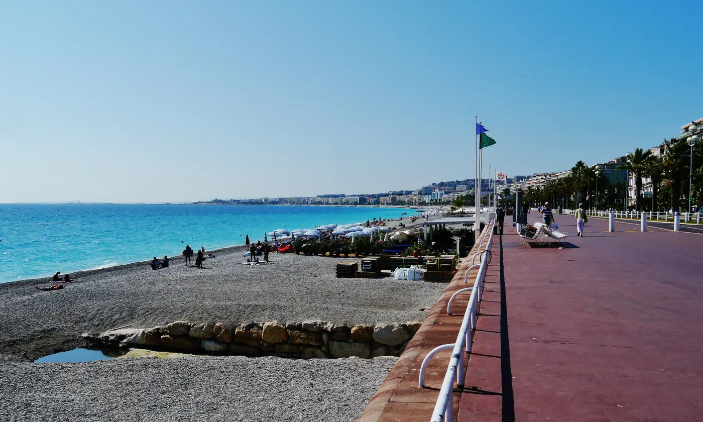 La Promenade des Anglais bordée de palmiers, avec la plage de galets et la mer turquoise de la baie des Anges, Nice