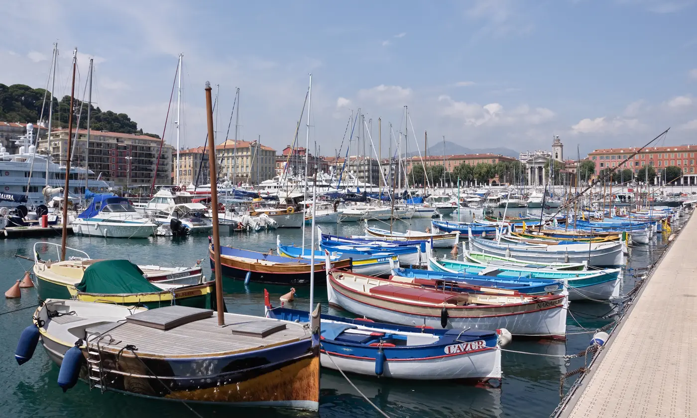 Pointus colorés amarrés dans le port Lympia, façades et clocher de Notre-Dame du Port en arrière-plan, Nice