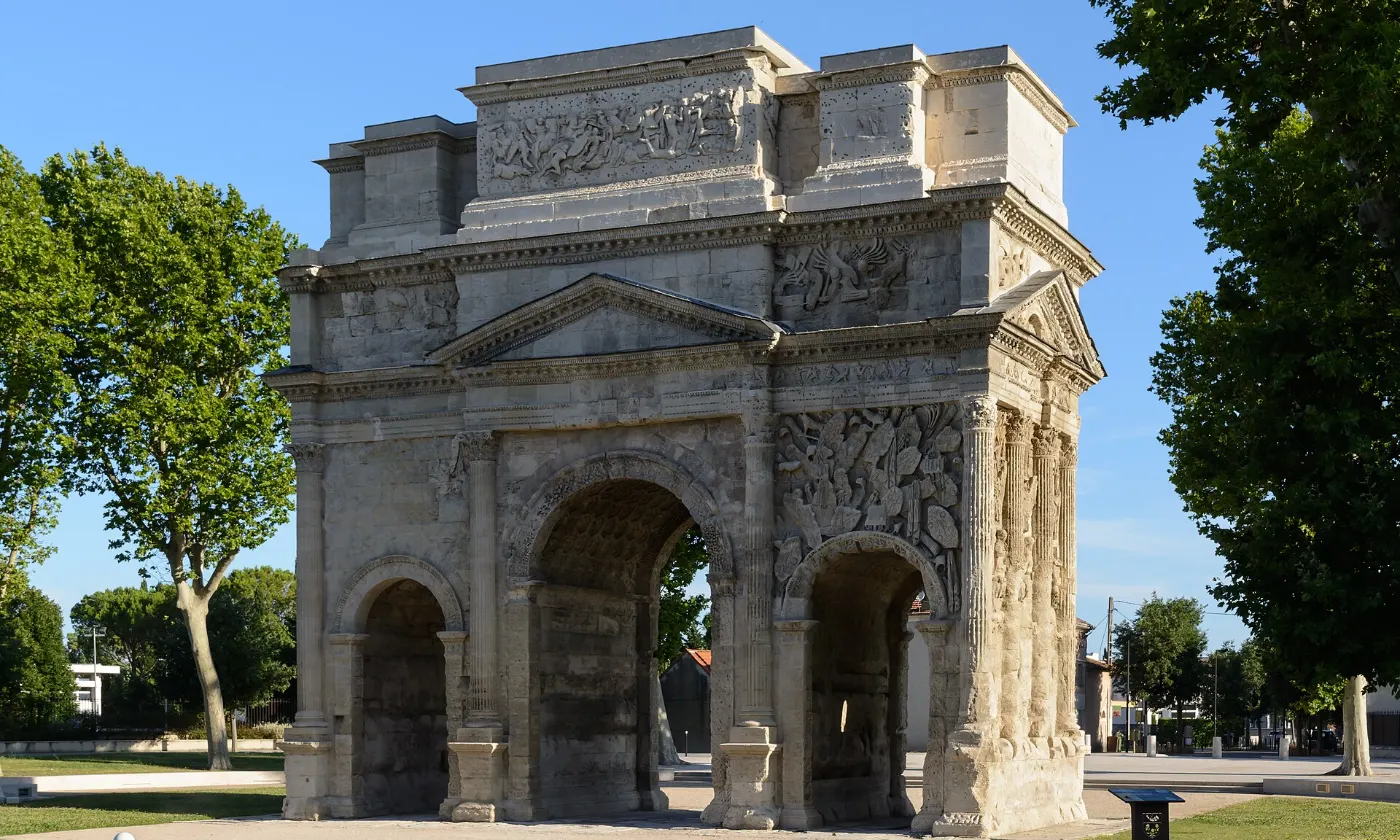 L'arc de triomphe romain d'Orange et ses bas-reliefs, encadré d'arbres
