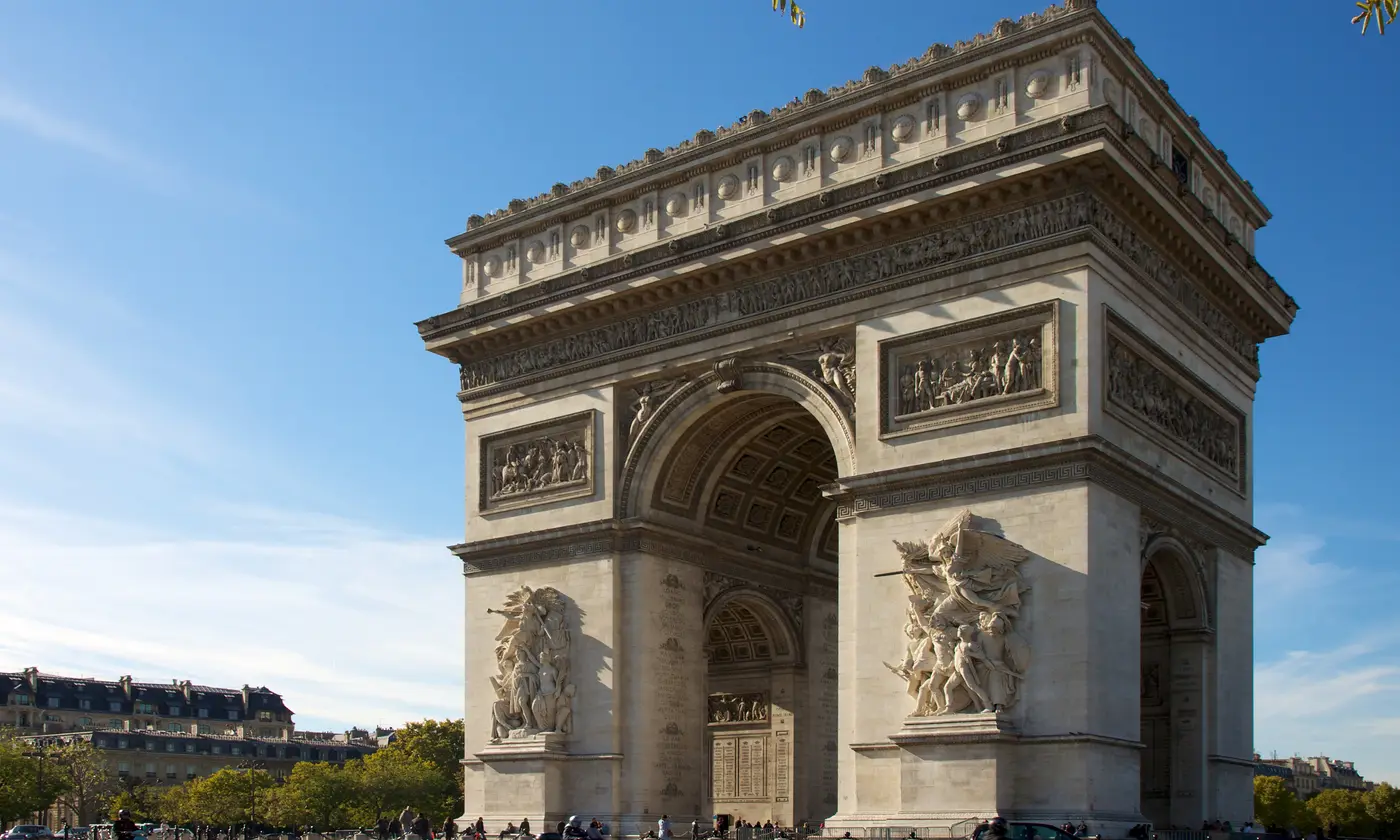 L'Arc de Triomphe baigné de lumière dorée sous un ciel bleu, en haut des Champs-Élysées, Paris