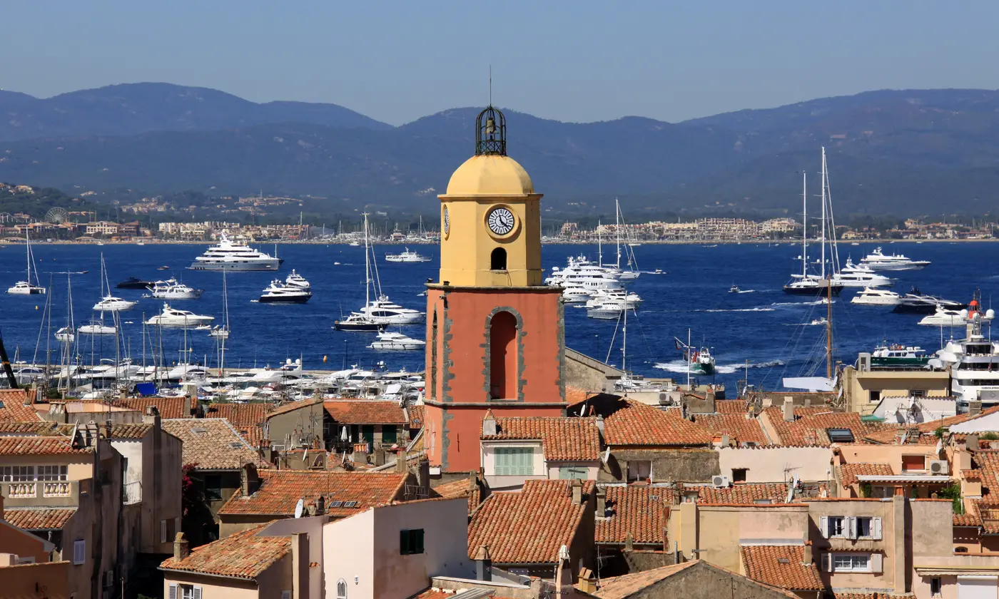Le clocher ocre et jaune émergeant des toits de tuiles, face au golfe parsemé de yachts, Saint-Tropez