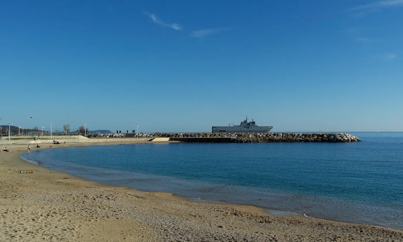 Courbe de sable des plages du Mourillon, eau claire et digue face à la rade, Toulon